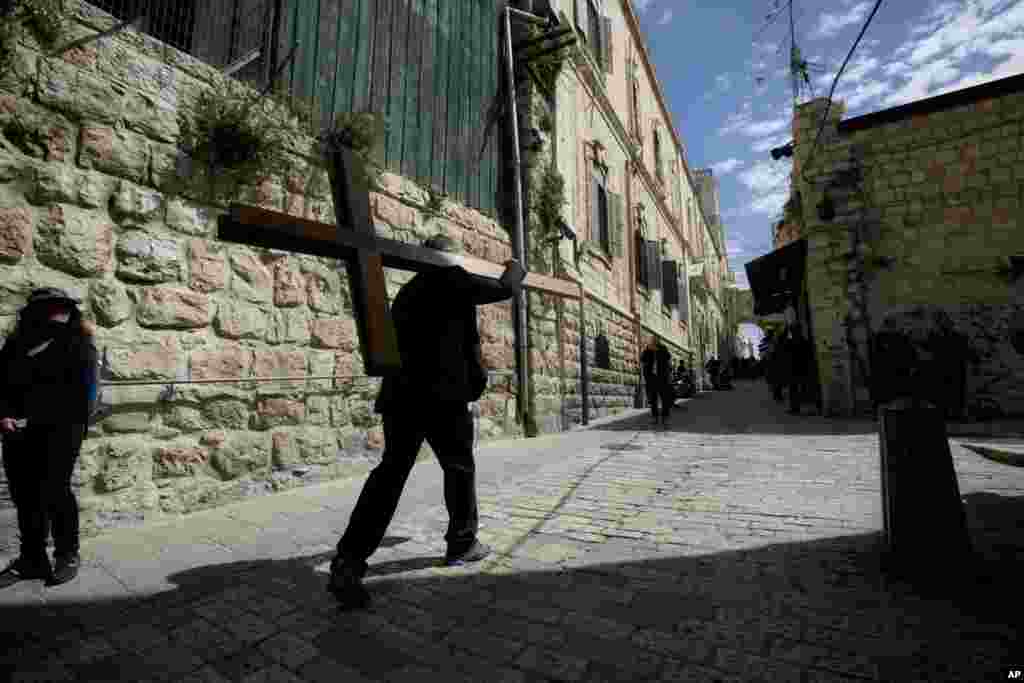 A man carries a cross during the Good Friday procession in Jerusalem's Old City, April 3, 2015.