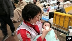 Japanese Red Cross Society worker feeds baby at relief center