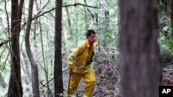 Lucas Handy de la brigada de bomberos voluntarios corta arbustos y maleza cerca a la zona del incendio.