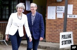La primera ministra británica Theresa May y su esposo Philip salen de votar en su distrito de Maidenhead, Inglaterra.