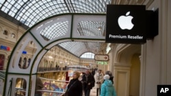 FILE - Shoppers pass an Apple Premium reseller inside the Moscow GUM department store. Russia’s economy has been battered this year by uncertainty over the conflict in Ukraine, lower oil prices, Western sanctions and retaliatory Russian import bans.