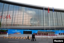 People walk past the China National Convention Center, a venue of the upcoming Belt and Road Forum in Beijing, May 12, 2017.