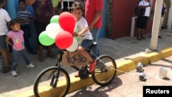 A child rides a bike adorned with balloons and a sign reading "Peje bici" (Peje bicycle in reference to Andres Manuel Lopez Obrador's nickname Peje) during the presidential election in Tepetitan, Mexico, July 1, 2018. 