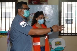 Heather Mack, dikawal oleh petugas imigrasi (kiri) setelah dibebaskan dari Penjara Kerobokan, di Rumah Detensi Imigrasi di Jimbaran , Badung, Bali, 29 Oktober 2021. (REUTERS/Johannes P. Christo)