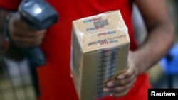 FILE - A worker of Indian e-commerce company Snapdeal.com scans barcode on a box after it was packed at the company's warehouse in New Delhi.