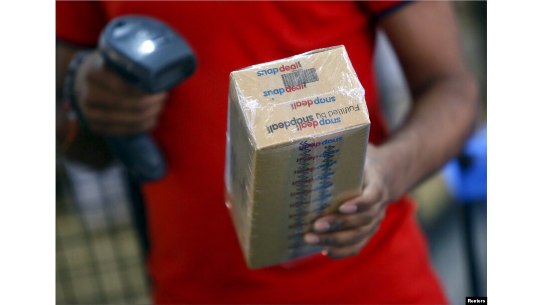FILE - A worker of Indian e-commerce company Snapdeal.com scans barcode on a box after it was packed at the company's warehouse in New Delhi.