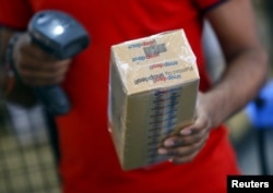 FILE - A worker of Indian e-commerce company Snapdeal.com scans barcode on a box after it was packed at the company's warehouse in New Delhi.
