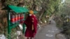 Seorang biksu Buddha Tibet di pengasingan memutar roda doa di jalan yang ditandai dengan lingkaran bagi para pemilih yang antre untuk memberikan suara, guna memastikan jarak sosial, selama pemilu di Dharamsala, India, Minggu (3/1). 