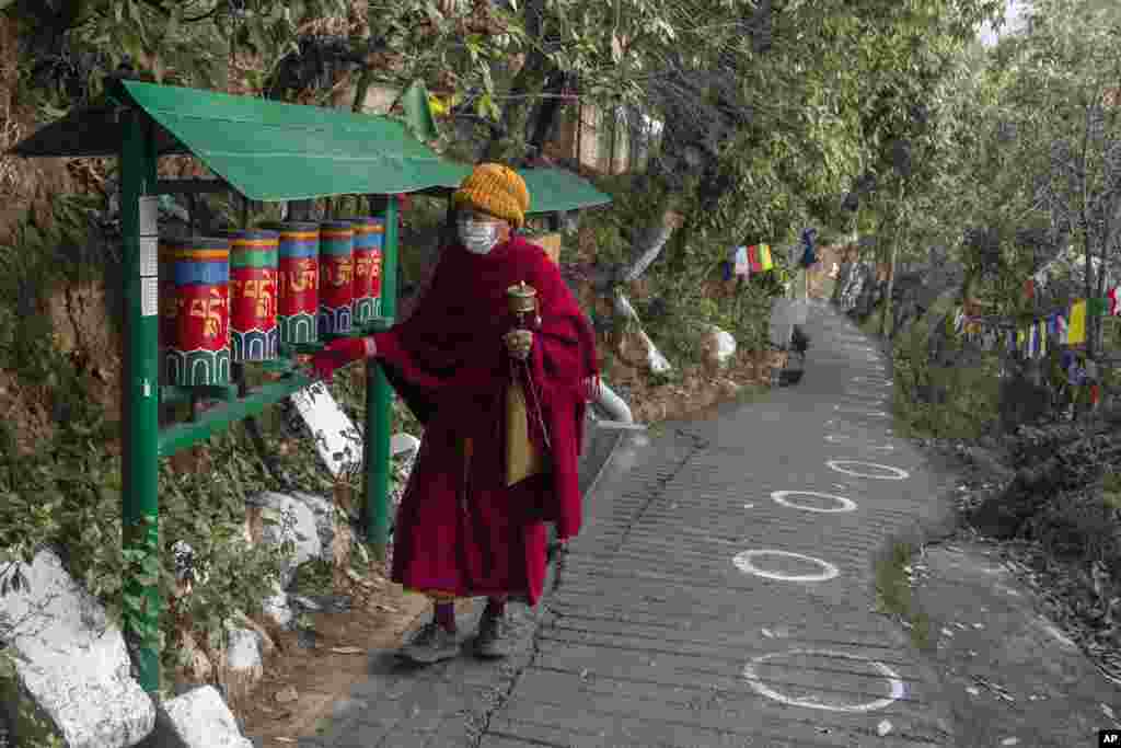 An exile Tibetan Buddhist monk rotates prayer wheels next to a path marked with circles for voters to ensure social distancing in Dharmsala, India.