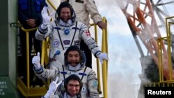 Dari atas ke bawah: Andreas Mogensen, Aidyn Aimbetov dan Sergei Volkov melambaikan tangan saat menaiki pesawat Soyuz TMA-18M di Baikonur Cosmodrome, Kazakhstan (2/9). (Reuters/Kirill Kudryavtsev)