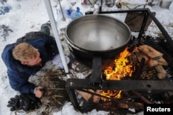 A man makes a fire under a large cooking pot in the Oceti Sakowin camp during the continuing protest of the Dakota Access pipeline, Nov. 29, 2016.