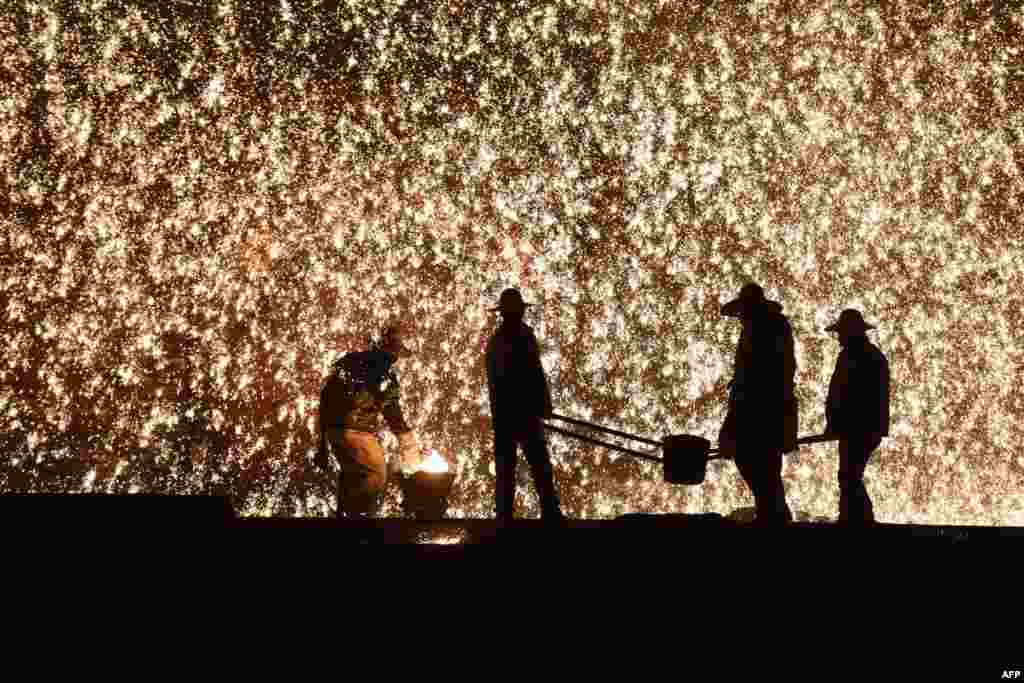 Ablacksmith (L) throws molten metal against a cold stone wall to create a shower of sparks, on the night before the Lantern Festival, which marks the end of Lunar New Year celebrations, in Nuanquan, China, February 18, 2019.