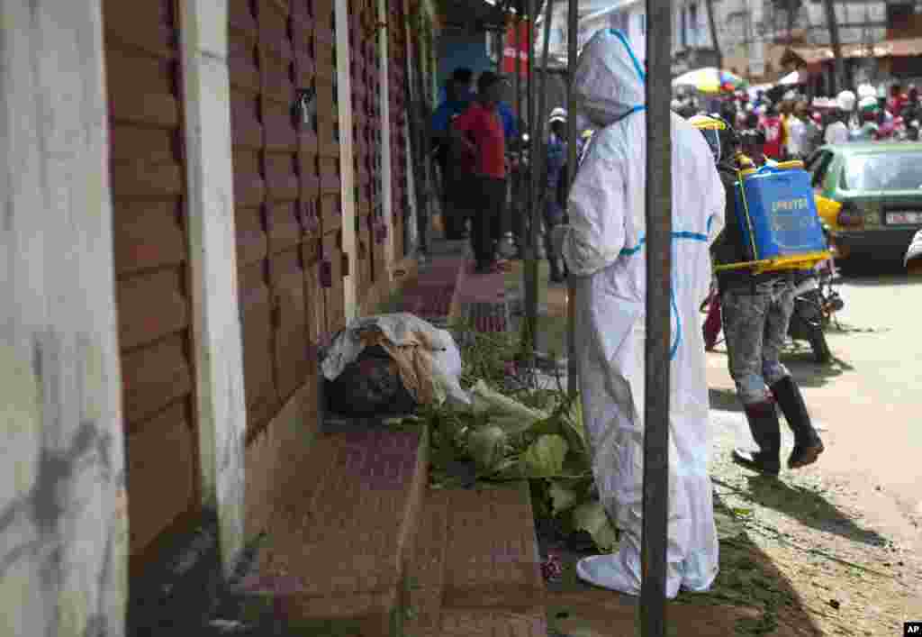 Heath workers collect samples from the body of a person suspected to have died from the Ebola virus, as it lies on the street covered in leaves in Freetown, Sierra Leone. Burial teams abandoned the bodies of Ebola victims in the capital after going on strike this week, though an official claimed the situation had been resolved. 