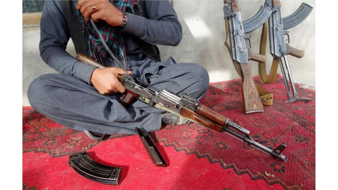 Seorang pedagang senjata membersihkan senapan serbu AK-47 miliknya di rumahnya di provinsi Laghman, 10 Desember 2012.