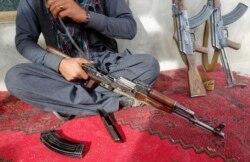 Seorang pedagang senjata membersihkan senapan serbu AK-47 miliknya di rumahnya di provinsi Laghman, 10 Desember 2012.