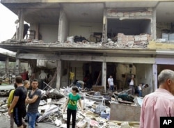 Photo released by Syrian official news agency SANA, Syrian citizens gather at the scene where two explosions struck in the village of Mukharam al-Fawkani, east of the central city of Homs, Syria, Thursday May 5, 2016.