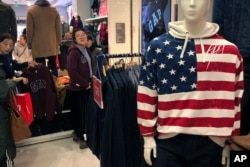 FILE - A woman tries out a sweater at U.S. retailer GAP's flagship store in Beijing, Jan. 10, 2019.