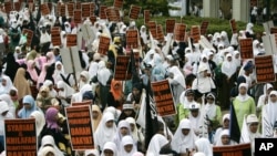 FILE - "Capitalism sucks the peoples' blood" and "Uphold Sharia and Islamic government," Indonesian members of Hizbut Tahrir, a conservative Islamic group, protest against capitalism, Jakarta, Indonesia. 