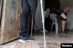 Palestinian woman Nazeeha Qudeih, 38, who, according to medics, lost her right leg after she was shot by Israeli forces during a protest at the Israel-Gaza border, puts on her artificial limb as her brother Suhaib, 33, who also lost a leg in the protests, stands at their house in Khan Younis in the southern Gaza Strip, April 1, 2019.
