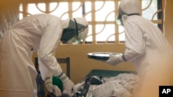 In this 2014 photo provided by the Samaritan's Purse aid organization, Dr. Kent Brantly, left, treats an Ebola patient at the Samaritan's Purse Ebola Case Management Center in Monrovia, Liberia.