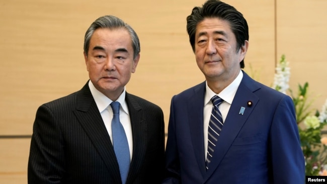 中国外长王毅在东京与日本首相安倍晋三握手。(2019年11月25日)