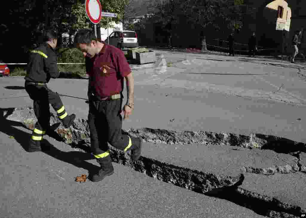 Petugas pemadam kebakaran memeriksa retakan di jalan akibat gempa di Norcia, Italia tengah (30/10).&nbsp;(AP/Gregorio Borgia)