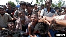 Un jeune garçon est extrait de la foule alors que des réfugiés Rohingya se battent en faisant la queue pour rentrer au bazar Cox, au Bangladesh, le 26 septembre 2017.