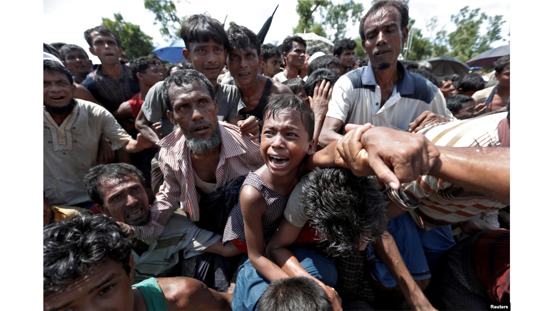 A boy is pulled to safety as Rohingya refugees scuffle while queueing for aid at Cox's Bazar, Bangladesh, Sept. 26, 2017.