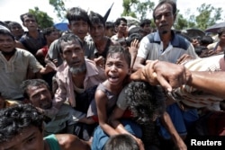 FILE - A boy is pulled to safety as Rohingya refugees scuffle while queueing for aid at Cox's Bazar, Bangladesh, Sept. 26, 2017.