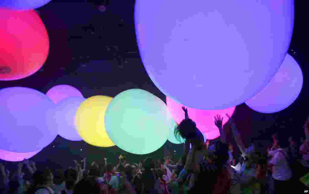 Visitors reach out for colorful balloons "Sound Spheres" as they enjoy immersing their bodies in light art and interactive music world by teamLab Jungle and Future Park in Tokyo, Aug. 28, 2017. 