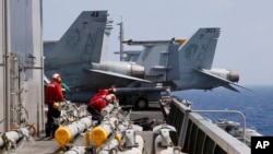FILE - U.S. Navy crewmen from the U.S. Navy aircraft carrier USS Carl Vinson (CVN 70) prepare to load missiles to F-18 fighter jets prior to a routine patrol off the disputed South China Sea Friday, March 3, 2017. Philippines South China Sea-US Military
