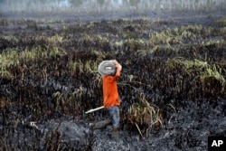 A fireman prepares to extinguish forest fire in Ogan Ilir, South Sumatra, Indonesia, Sept. 17, 2015.