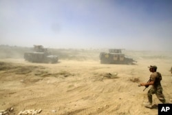 FILE - Iraqi security forces advance their positions during the fight against Islamic State militants in Fallujah, Iraq, June 15, 2016.