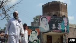 FILE - Pedestrians walk past the assassination site of opposition leader Benazir Bhutto in Rawalpindi.