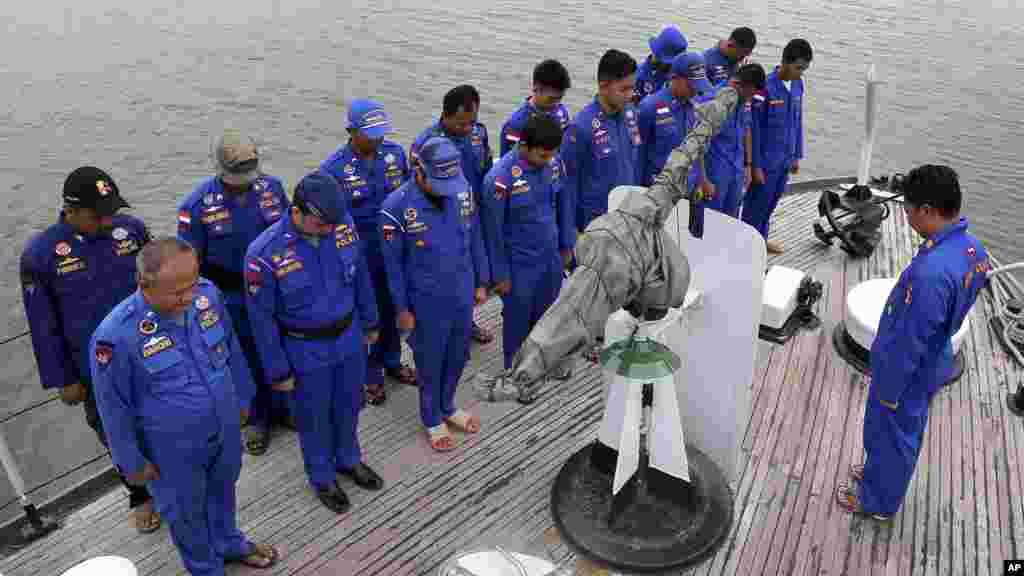 Les membres de la police maritime de l&#39;Indonésie prient à bord d&#39;un navire de recherche et de sauvetage avant une opération de recherche de l&#39;avion d&#39;AirAsie&nbsp; disparu, au port de Pangkal Pinang dans l&#39;île de Sumatra, en Indonésie, le 29 décembre 2014.