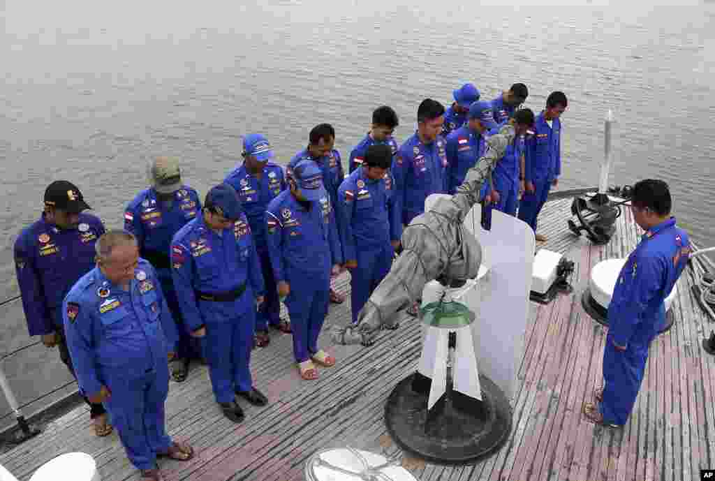 Members of Indonesia&#39;s Marine Police pray on board a search and rescue ship before a search operation for the missing AirAsia flight 8501, at Pangkal Pinang port in Sumatra Island, Indonesia, Dec. 29, 2014.