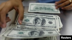 ရန်ကုန်မြို့က ငွေလဲကောင်တာတခုမှာ အမေရိကန်ဒေါ်လာတွေ ရေတွက်နေသူတဦး။ (မေ ၂၃၊ ၂၀၁၃)