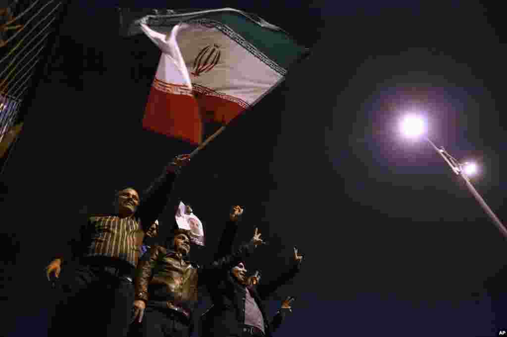 Iranians wave their national flag as they hold a poster of President Hassan Rouhani, while welcoming Iranian nuclear negotiators upon their arrival from Geneva in Tehran, Nov. 24, 2013.