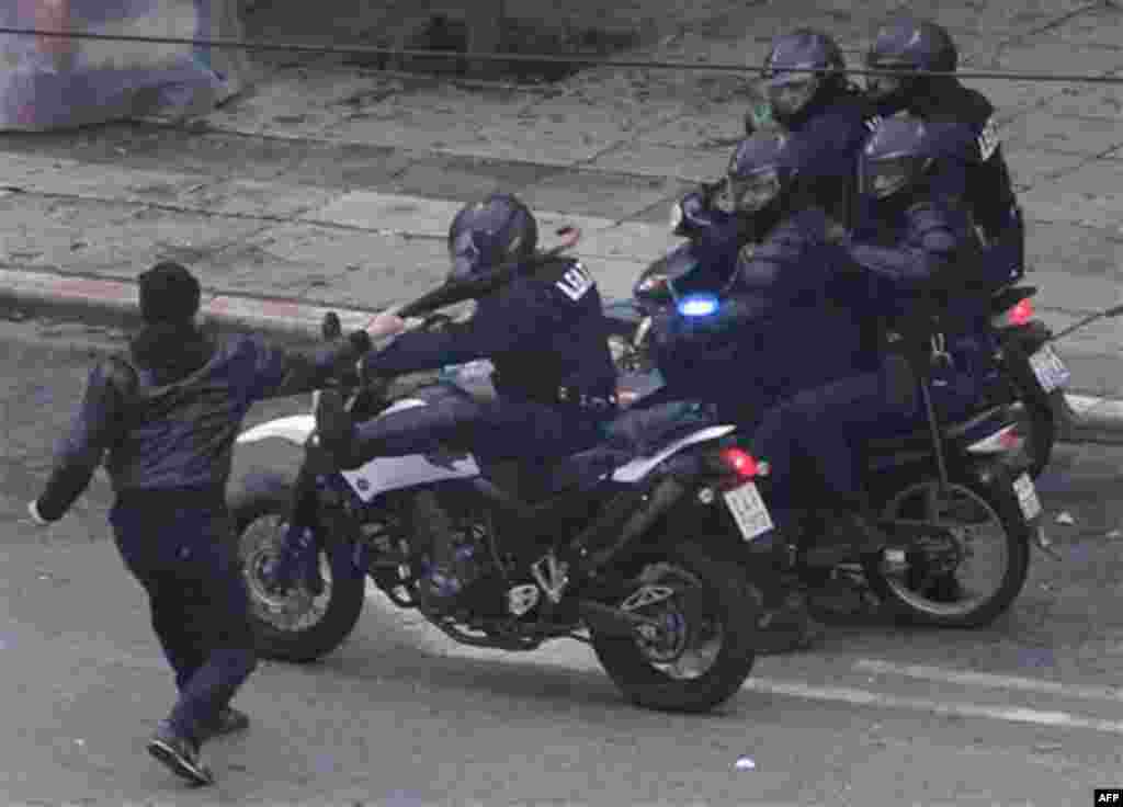 A protester clashes with policemen on motorcycles, during a demonstration in Athens, Wednesday, Dec. 15, 2010. Hundreds of protesters clashed with riot police across central Athens, smashing cars and hurling gasoline bombs during a massive labor protest 