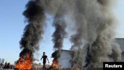 A demonstrator walks near burning tires during ongoing anti-government protests in Tripoli, Lebanon, Nov. 12, 2019. 