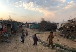 FILE - Children play outside their family's shelters at an Afghan refugee camp in Islamabad, Pakistan, Feb. 13, 2020.