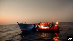 Migrants sailing in a crowded wooden boat carrying more than seven hundred migrants, are helped by members of an NGO during a rescue operation at the Mediterranean sea, about 13 miles north of Sabratha, Libya, Aug. 29, 2016. 