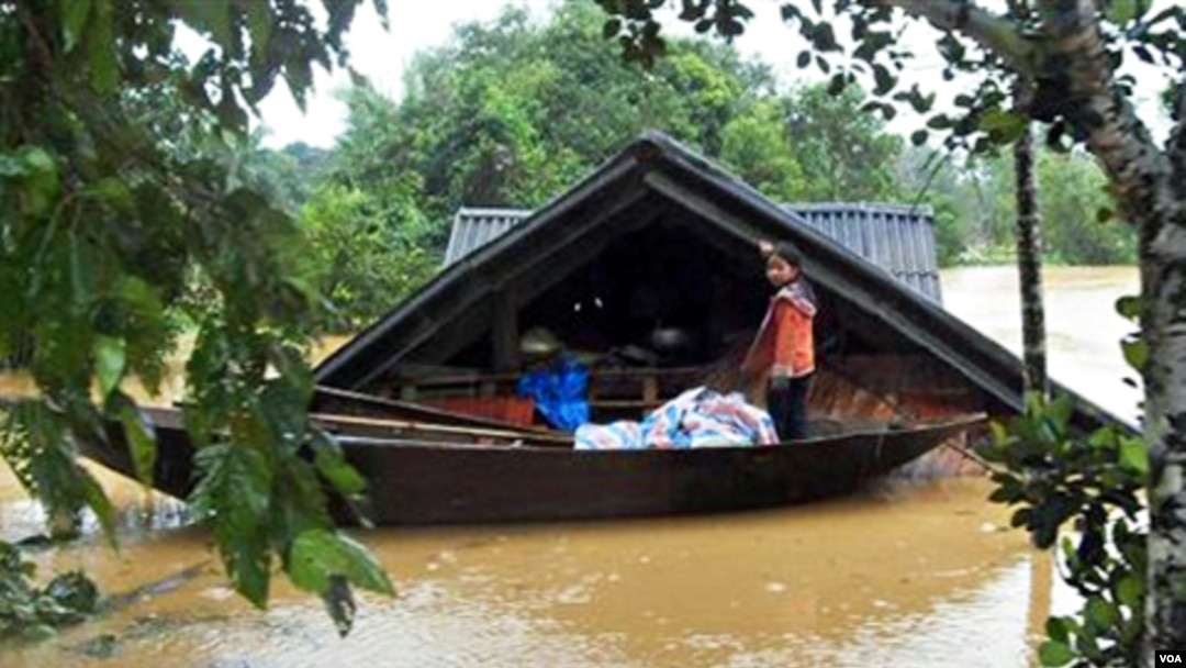 Seorang anak perempuan Vietnam berdiri di atas perahu di depan rumahnya yang terendam air minggu lalu. Banjir parah menewaskan paling sedikit 30 orang di Vietnam tengah.