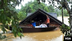 Seorang anak perempuan Vietnam berdiri di atas perahu di depan rumahnya yang terendam air minggu lalu. Banjir parah menewaskan paling sedikit 30 orang di Vietnam tengah.