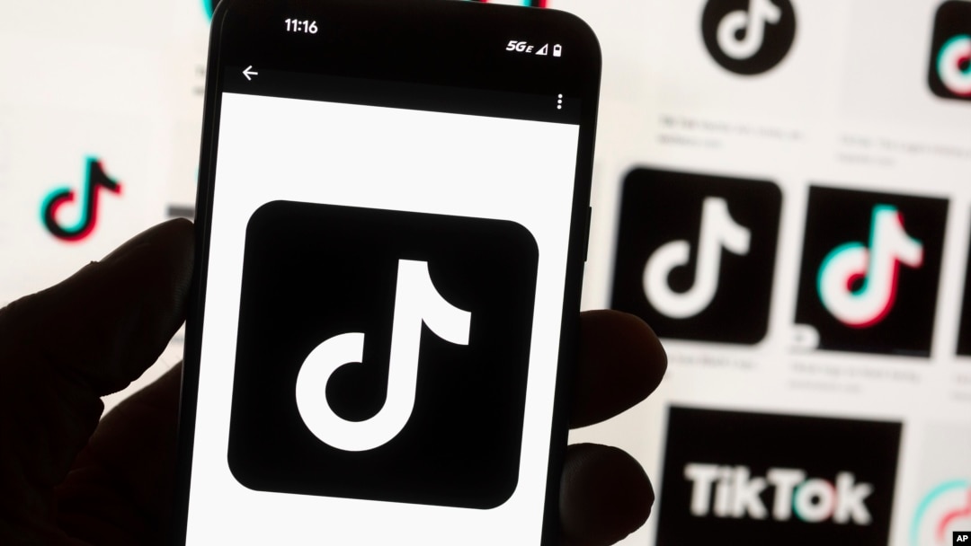 Arhiva - Logo TikToka na mobilnom telefonu isred monitora kompjutera, 14. oktobra 2022.