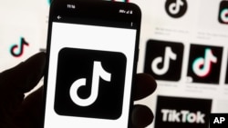 FILE - The TikTok logo is displayed on a mobile phone in front of a computer screen, Oct. 14, 2022. TikTok announced on Sept. 23, 2024, that it had removed accounts of Russian state media organizations, accusing them of "covert influence operations."