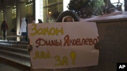 A demonstrator holds a poster reading "We are for Dima Yakovlev Bill" outside the Federation Council. The bill is named in honor of Dima Yakovlev, a Russian toddler who was adopted by Americans and then died in 2008 after his father left him in a car in broiling heat for hours, December 26, 2012. 