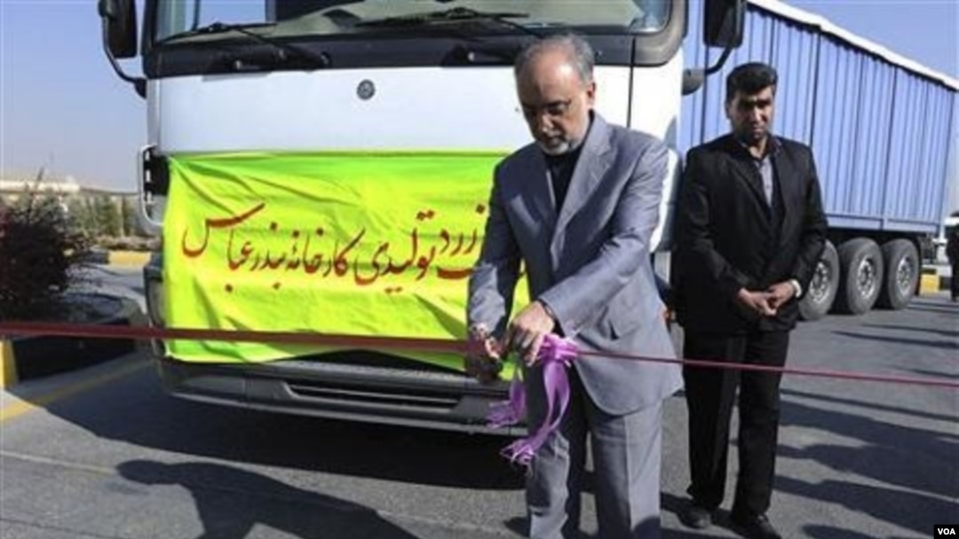 Kepala Badan Energi Atom Iran, Ali Akbar Salehi, memotong sebuah pita peresmian di fasilitas pengolahan uranium di Isfahan, dengan truk di belakangnya berisi bubuk uranium produksi dalam negeri Iran.