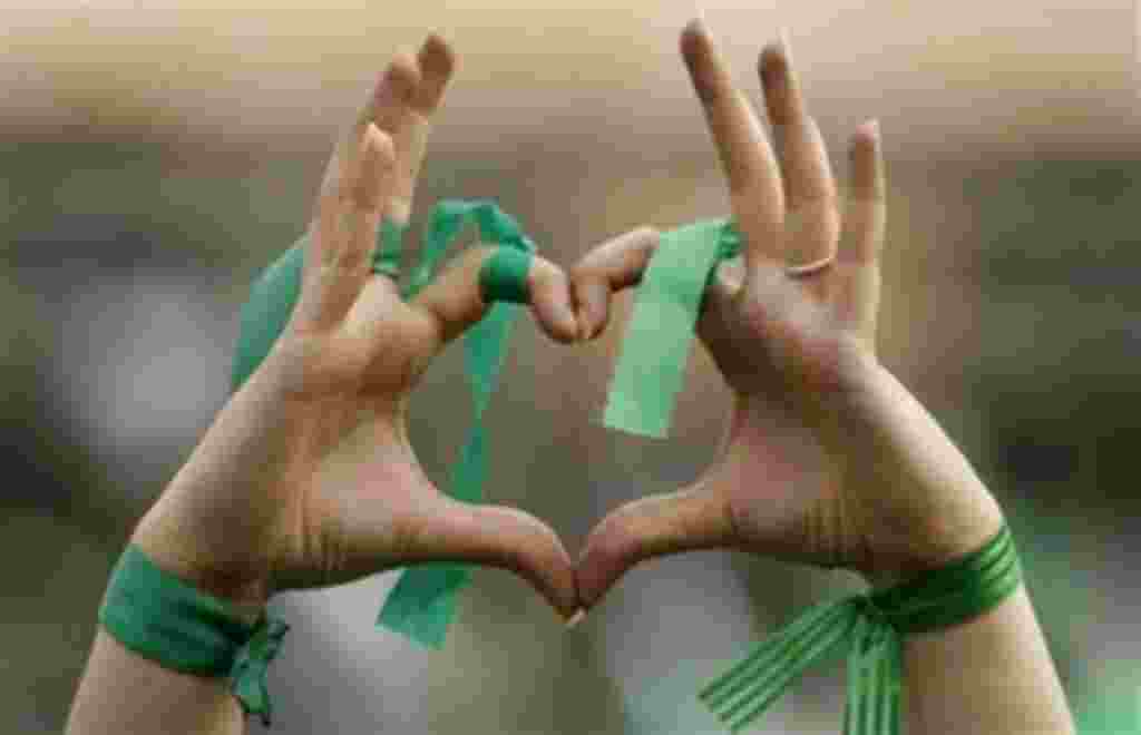 A supporter of main challenger and reformist candidate Mir Hossein Mousavi forms a heart shape with her hands to indicate her support, while wearing green ribbons - the color of the party, amidst a festive atmosphere at an election rally rally in Tehran, 