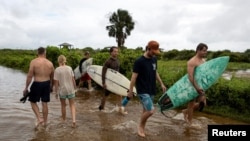 La gente camina a través de una entrada inundada a la playa mientras la tormenta tropical Debby se mueve desde Georgia hacia el Atlántico Norte, en Isle of Palms, Carolina del Sur, EE.UU., 6 de agosto de 2024. REUTERS/Marco Bello